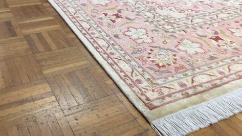 A pink and white patterned rug with tassels adds a charming touch to the hardwood floors.