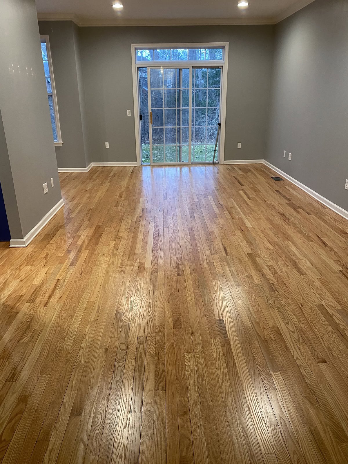 Hartford home living area with refinished oak hardwood flooring, spacious open room, and sliding glass doors with natural light