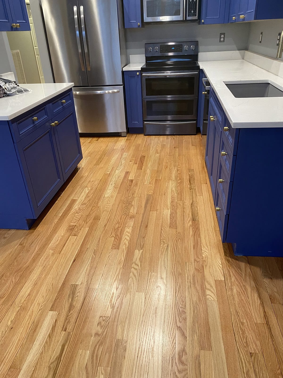 Hartford kitchen with natural oak hardwood flooring, blue cabinets, and modern stainless steel appliances