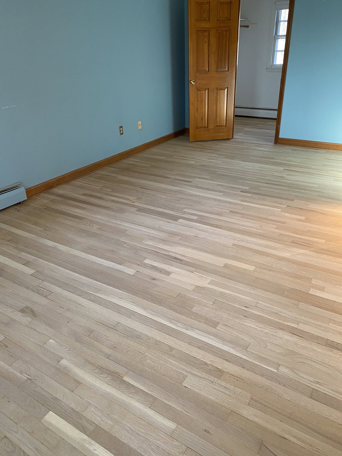 Light oak hardwood flooring in Wethersfield bedroom with natural finish, smooth plank layout, and clean residential interior