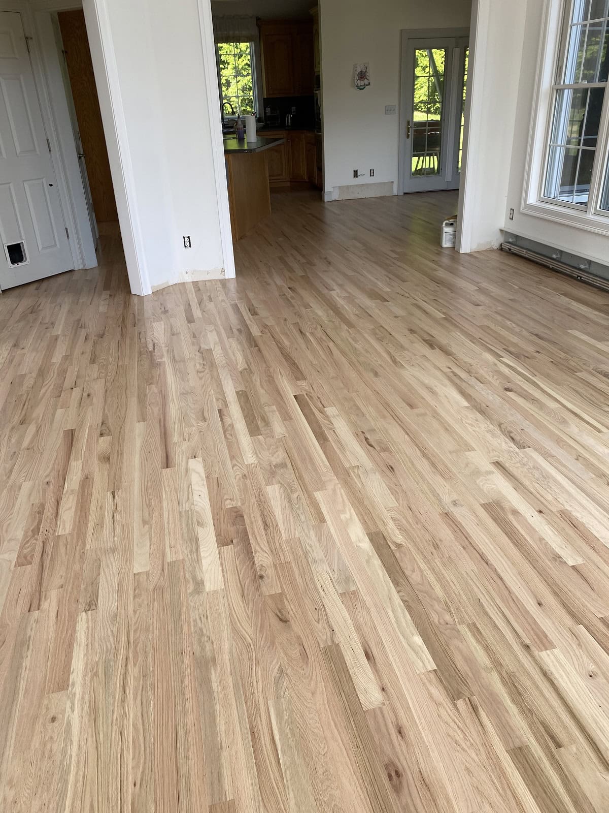 Natural oak hardwood flooring installation in open-concept kitchen and living area in Tolland home with smooth finish and warm wood tones
