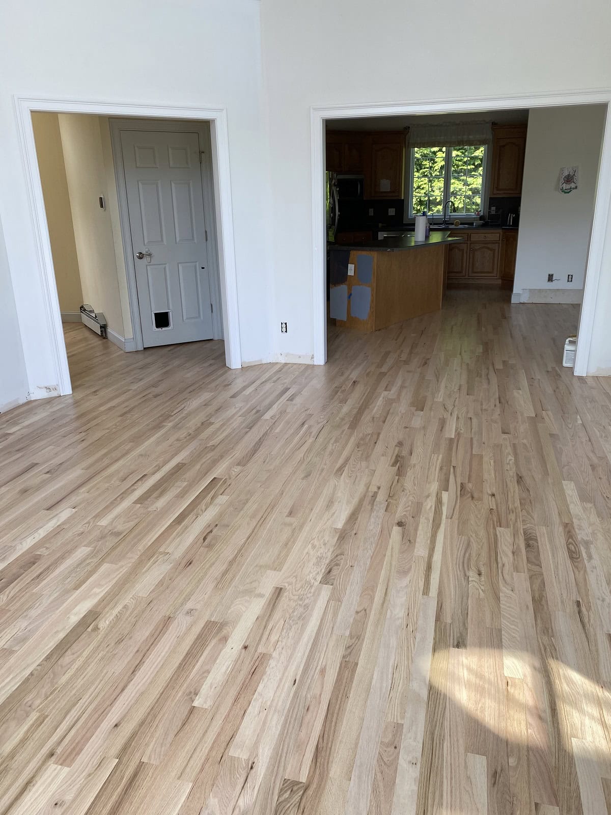 Refinished oak hardwood flooring in Tolland home open living area with natural light, smooth finish, and consistent wood grain throughout