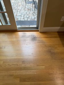 Badly worn hardwood flooring near a patio door before hardwood floor refinishing in the Walden Court area of Berlin CT 06037