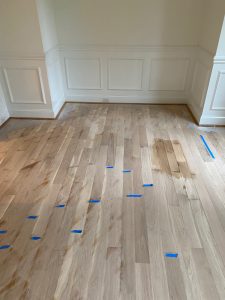 White oak hardwood floor in Canton CT 06019 with blue tape identifying pet-stained boards that required removal and replacement