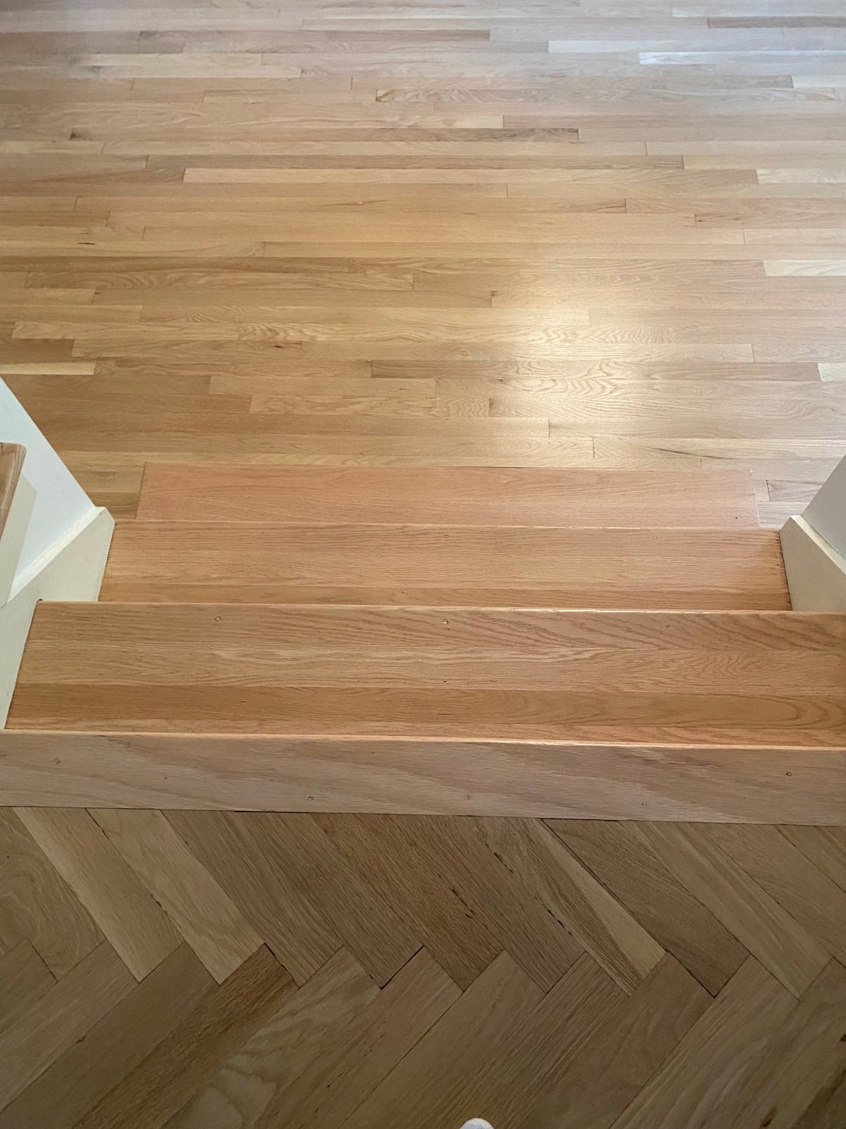 Finished hardwood floor refinishing project with red oak stair treads and white oak herringbone flooring in Devonwood, Farmington CT.