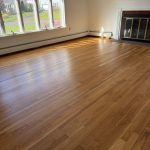 Professionally refinished oak hardwood floors in a New Britain Connecticut living room with fireplace and large windows.
